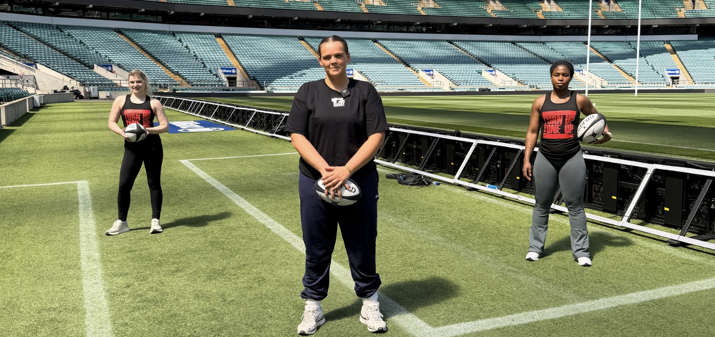 3 Ladies Standing hold rugby balls
