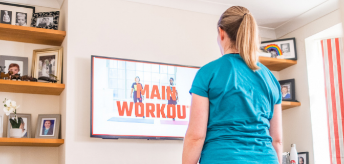 A woman looks at a exercise workout on a tv screen