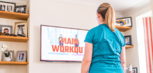 A woman looks at a exercise workout on a tv screen