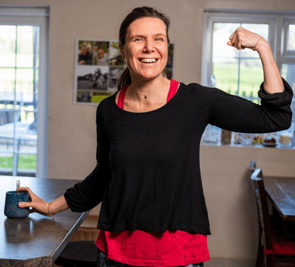 Woman smiles as she holds a cup of tea after exercising